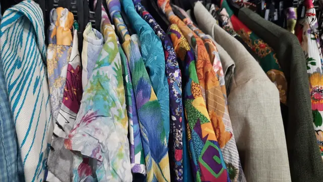 古着店のハンガーに並ぶ、色や柄の異なる衣服の資料写真。投稿者のTシャツやDollarama店内ではありません。