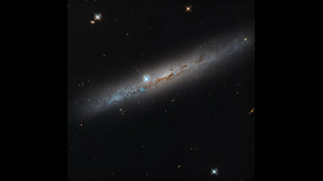 ハッブルが捉えたNGC 1827。斜めに伸びる円盤を塵の帯が横切り、中央付近に前景の明るい星が重なる。