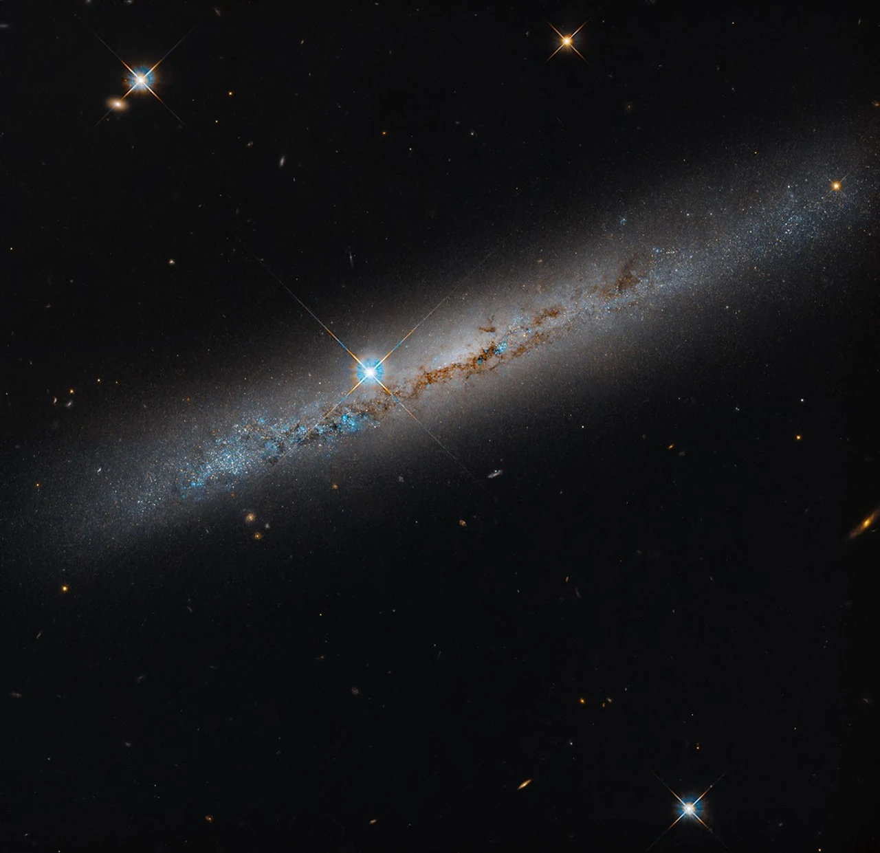 ハッブルが捉えたNGC 1827。斜めに伸びる円盤を塵の帯が横切り、中央付近に前景の明るい星が重なる。